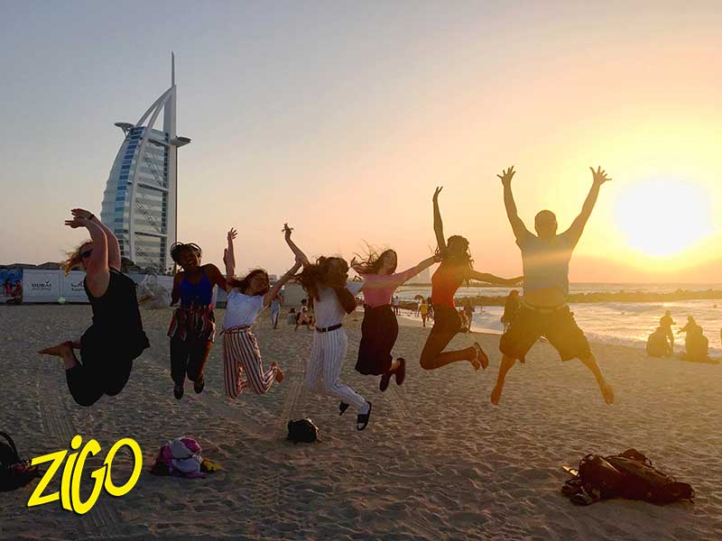 groupe de jeunes sautant pour la photo devant le Burj Arab