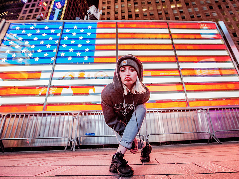 une jeune devant un drapeau des USA lumineux
