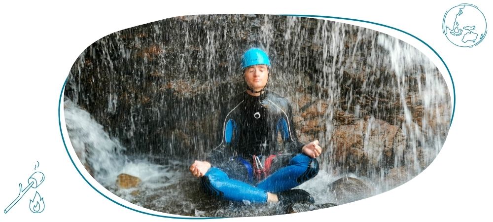 jeune homme assis en position de meditation sous une cascade d'eau durant une activité rafting de la colonie de vacances zigotours