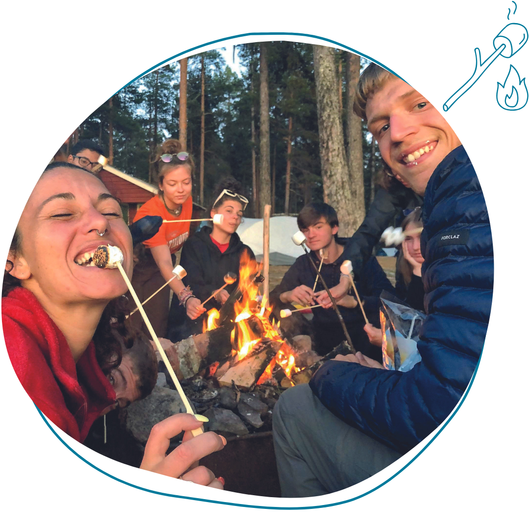 jeunes adultes qui mangent des chamallows grillés au coin du feu en colonie de vacances