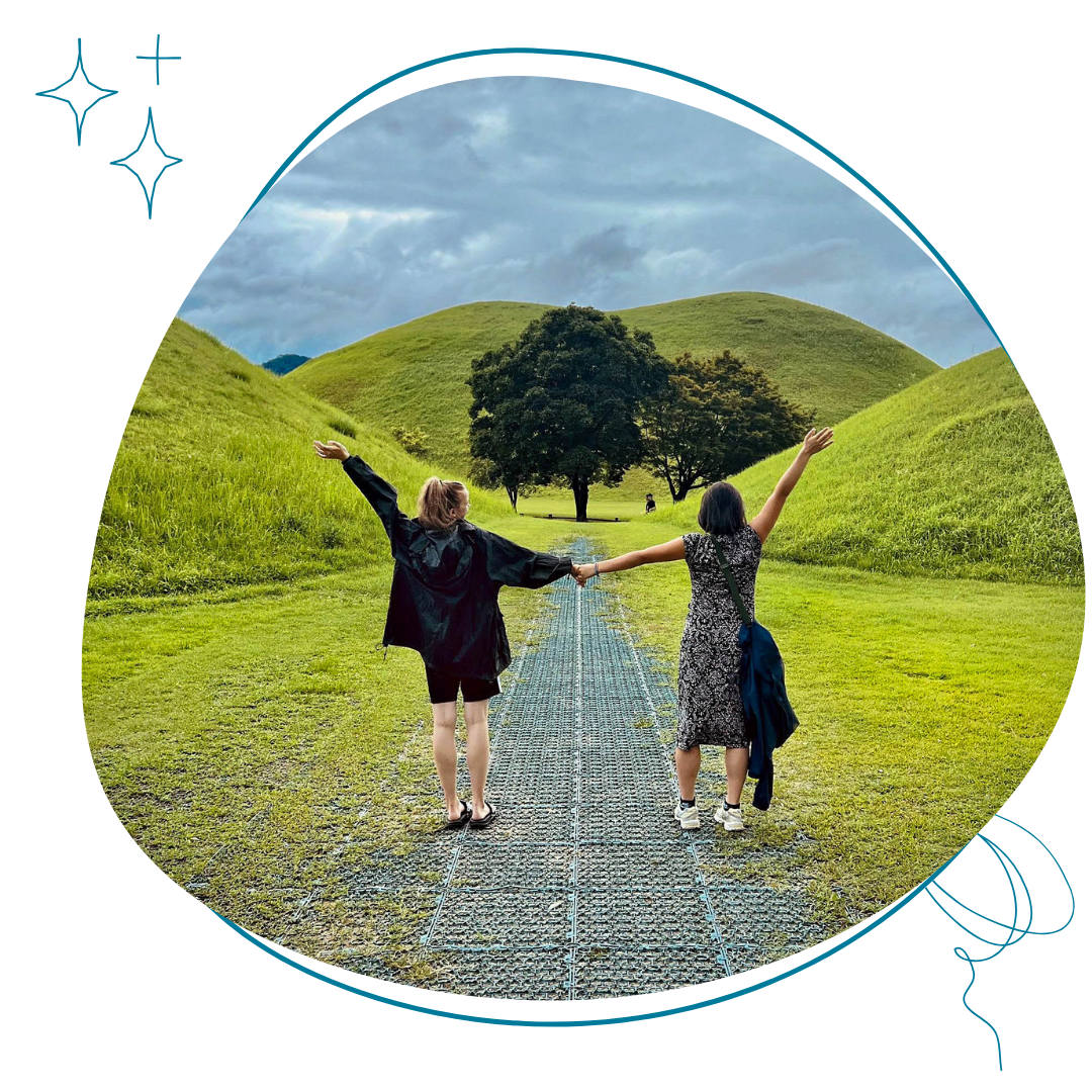 deux adolescentes qui de dos qui se tiennent la main devant un paysage verdoyant