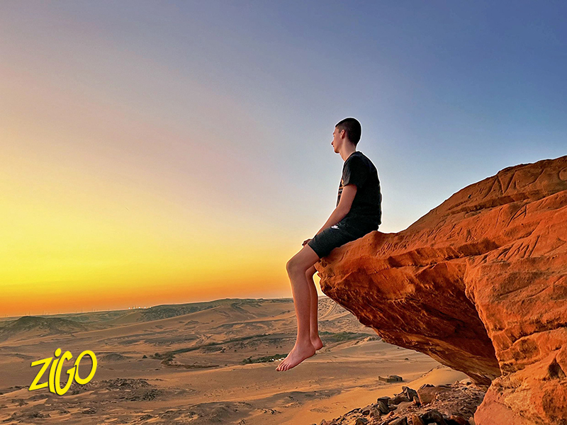 jeune sur un rocher au coucher du soleil