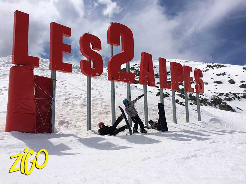 un jeune devant le panneau des 2 Alpes