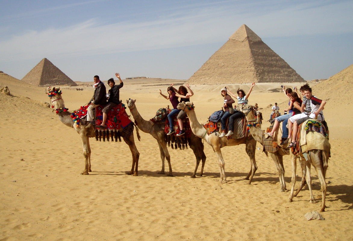 groupe sur des dromadaires devant des pyramides